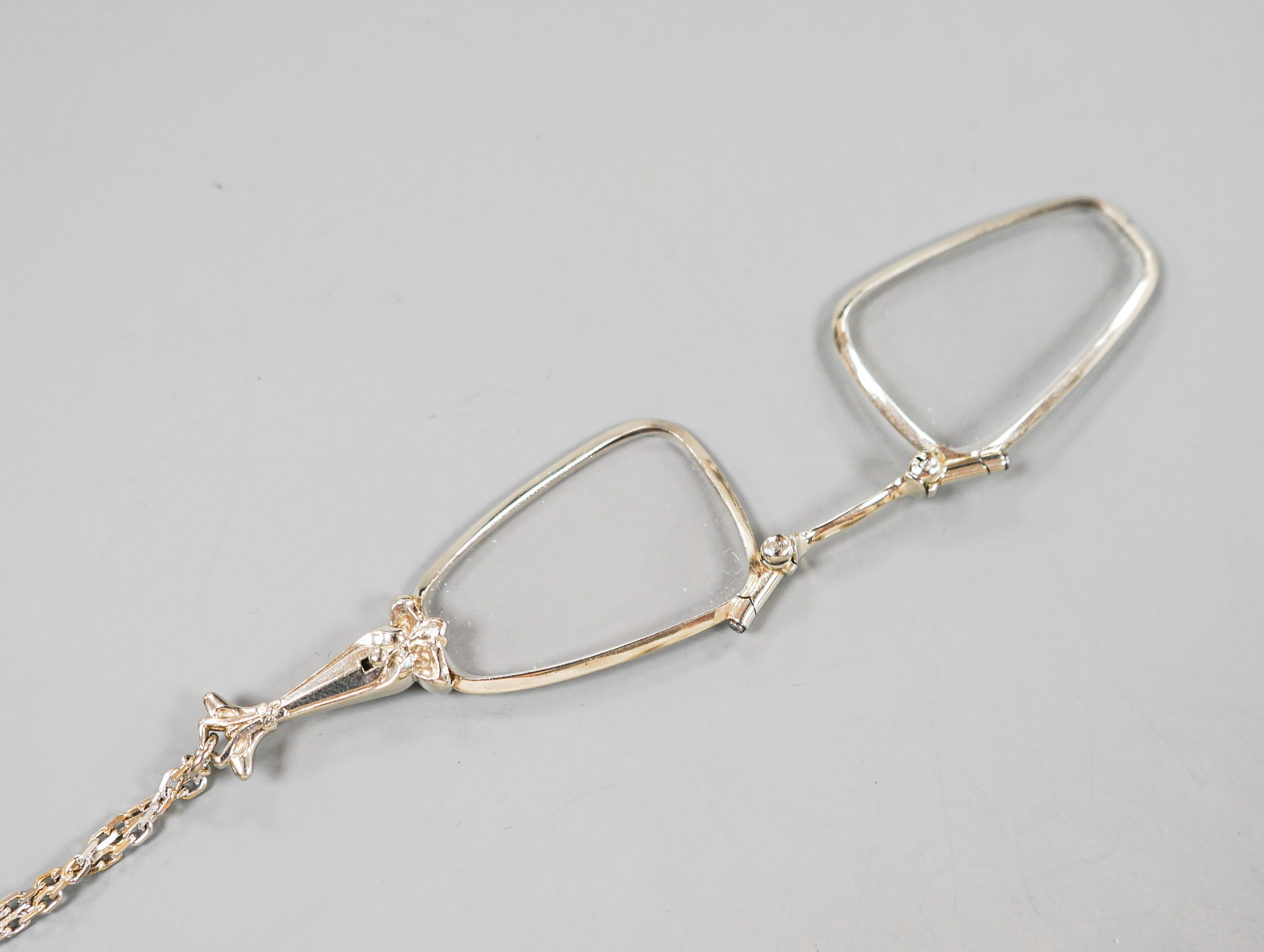 A modern 14k white mounted lorgnettes, 62mm, gross 14.1 grams, on a modern 750 white metal chain, 80cm, 14 grams.